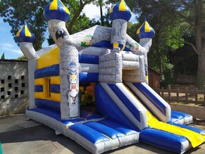 An inflatable castle with blue and yellow stripes, a slide, and cartoon character designs.
