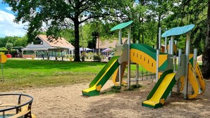 Une aire de jeux avec des toboggans et des balançoires dans un parc.
