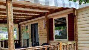 Un porche couvert avec une balustrade en bois, une fenêtre avec des volets rouges et un panneau indiquant le numéro « 21 » sur la balustrade.