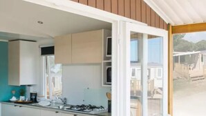 Uma cozinha compacta com armários brancos, um fogão e uma janela com vista para uma área residencial.