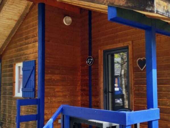 Una cabaña de madera con un porche azul y una puerta negra.