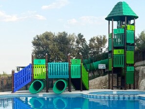 A pool area with a slide, a climbing structure, and a lookout tower. - Mobile Home 3 Bedrooms - Private Terrace (Calvisson)