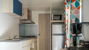 Una cucina compatta con piano cottura a gas, forno a microonde e frigorifero.