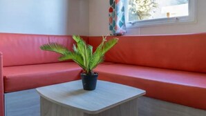 Una stanza con un divano rosso, un tavolino e una pianta in vaso.