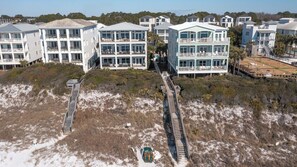 Ein Küstenhotel mit mehreren Gebäuden, einem Sandstrand und einer Holzpromenade, die zum Strand führt.