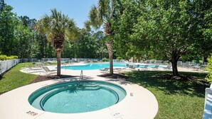 Una piscina circular con hidromasaje, rodeada de sillas de descanso y palmeras.
