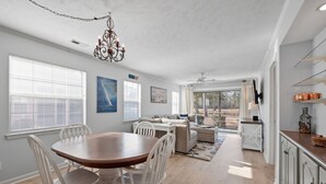 Una cocina amplia con comedor, armarios blancos y vistas al exterior.