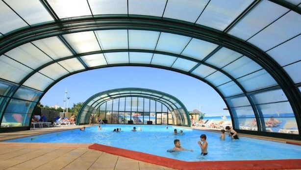 An indoor swimming pool with a glass ceiling and tiled floor. - Mobile home with terrace for 4 people, near the beach (La Faute-sur-Mer)
