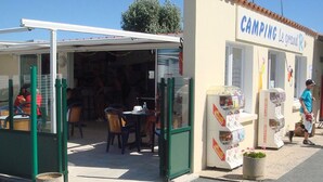 A small outdoor café with tables and chairs, a covered seating area, and a building labeled "CAMPING Le grand R." - Mobile home with terrace for 4 people, near the beach (La Faute-sur-Mer)