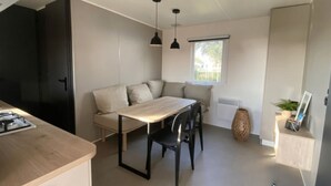 Un espace de vie compact comprenant une table à manger, des chaises, un canapé, une fenêtre et une petite plante.