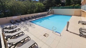 En pool med solstolar och en kakelbeklädd poolterrass.