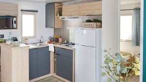 A compact kitchen with a central island, a built-in microwave, and a refrigerator. - Mobile Home with Terrace for 4 People in La Faute-sur-Mer (La Faute-sur-Mer)