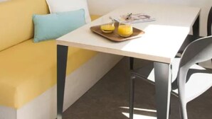 A small, bright room with a yellow sofa, a white table, and a grey chair. - Mobile home for 2 with terrace (Sandrans)