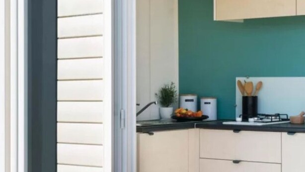 A kitchen with white cabinets, a teal backsplash, and a black countertop. - Mobile home for 2 with terrace (Sandrans)