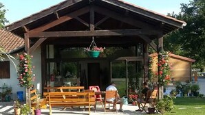 A covered outdoor seating area with benches and hanging flower baskets. - Mobile home for 2 with terrace (Sandrans)