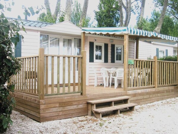 Une terrasse en bois avec un espace salon abrité et une petite table.