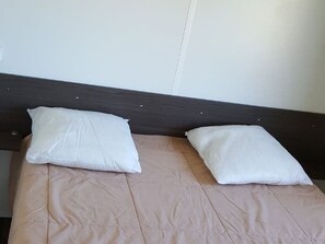 Un lit avec deux oreillers blancs et une couvre-lit beige.