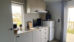 Une cuisine de taille réduite, équipée d’une cuisinière à gaz, d’un four à micro-ondes et de meubles blancs.