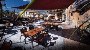 Eine Außenpatio mit Tischen und Stühlen, einem großen Sonnenschirm und einer Steinmauer.