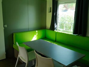 A room with a green sofa and a small table. There is a window with curtains. - 3-Bedroom Mobile Home with Terrace in Collias (Collias)