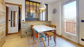 Un espace de salle à manger moderne avec une table blanche, des chaises en bois et un luminaire suspendu.