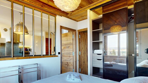Une chambre à coucher avec un grand lit, un plafond en bois et une armoire avec un miroir.