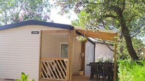 A mobile home with a wooden porch, a dining table, and chairs. - Mobile home for 6 with terrace (Laurens)