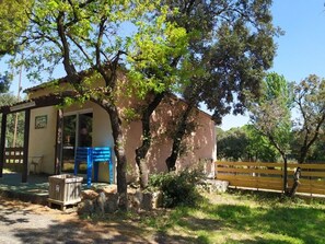 A rustic building with a covered porch, a wooden bench, and a stone wall. - Mobile home for 6 with terrace (Laurens)