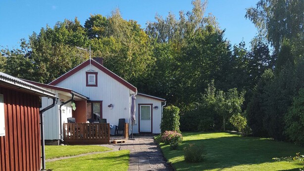 Ein Haus mit gepflasterter Auffahrt, die zu einer Haustür führt, umgeben von einem gepflegten Rasen und Bäumen.