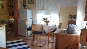Eine gemütliche Küche mit Essbereich, einem Kühlschrank, einem Tisch mit Stühlen und einem Fenster mit Vorhängen.