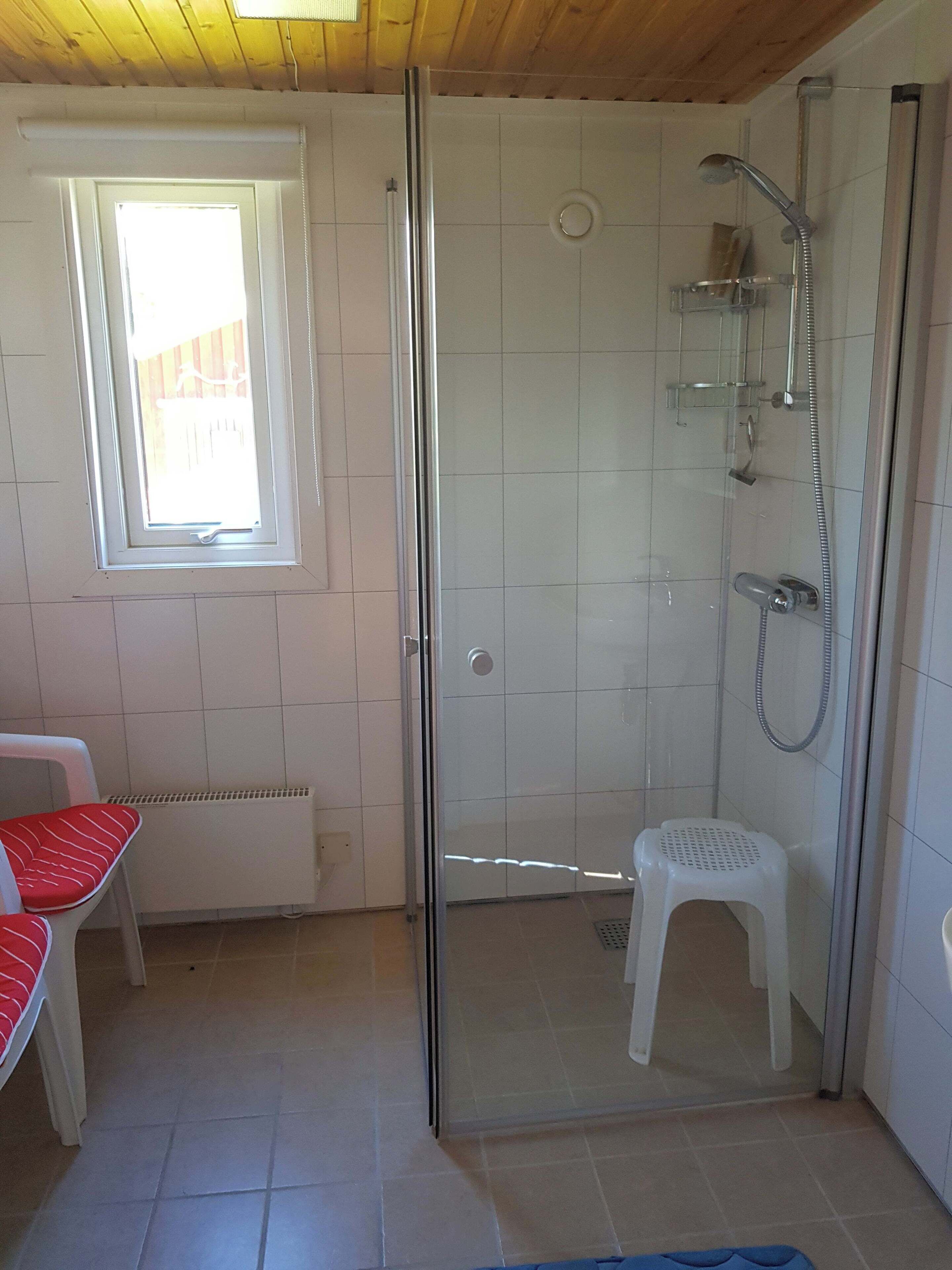 Une douche fermée par des parois en verre, dotée d’un pommeau de douche à main et d’un robinet à main.