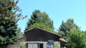 A small building with a tiled roof, a signboard, and a wooden fence.