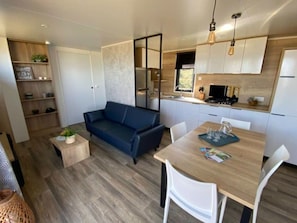 Un espace de vie moderne et compact comprenant un canapé, une table à manger et un coin cuisine.
