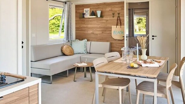 Een moderne woonkamer met een houten wand, een bank, een eettafel met stoelen en een keukenhoek.