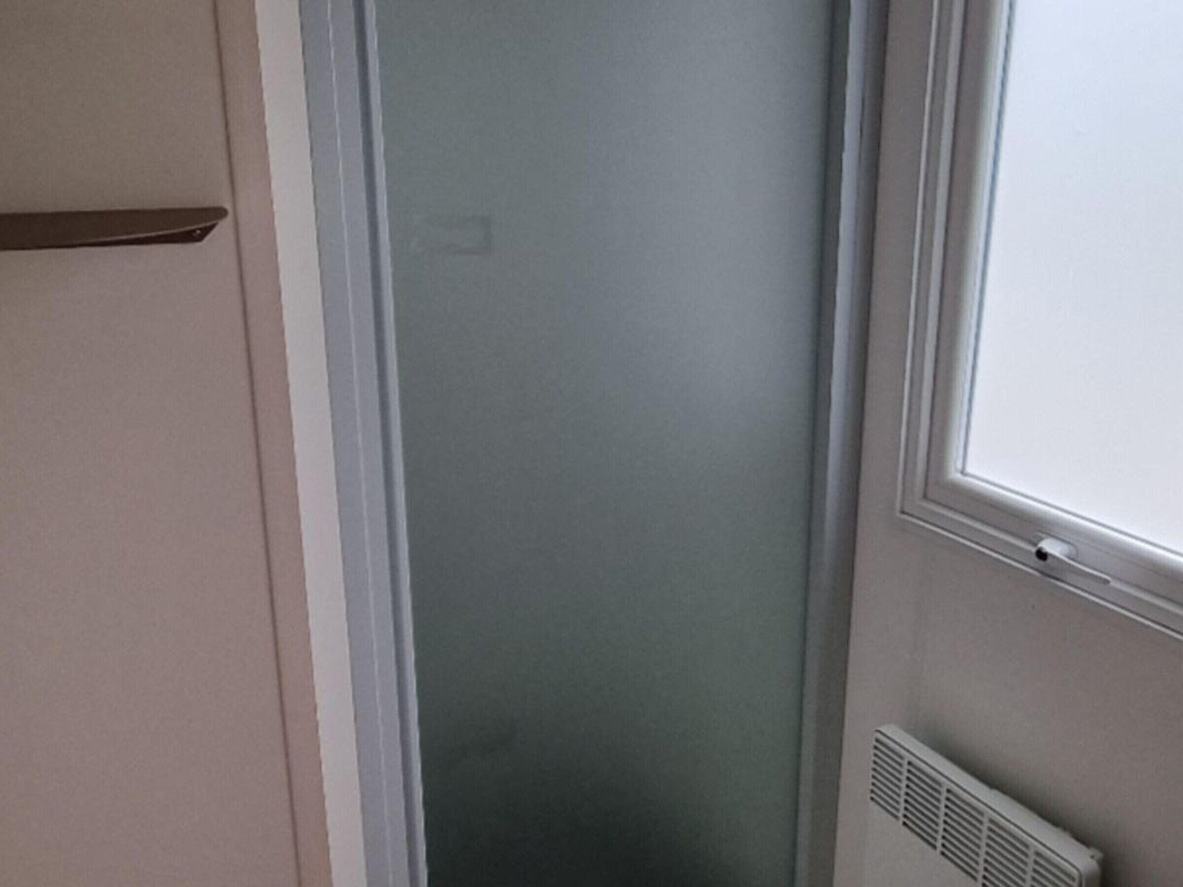 Een kamer met een schuifdeur, een radiator en een raam.