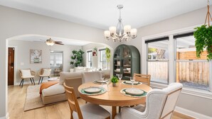 Uma sala de jantar com uma mesa redonda de madeira preparada para quatro pessoas, rodeada por cadeiras.