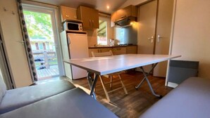 Eine kleine Küche mit Esstisch und Bank, einer Mikrowelle und einem Kühlschrank.