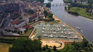 Luftaufnahme einer Flussstadt mit Brücke, einem Yachthafen und einer Kirche.