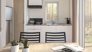 Eine moderne Küche mit weißen Schränken, einem eingebauten Herd und einem Fenster mit Blick auf einen Wald.