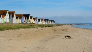 A beach with colorful beach huts and a dog on the sand. - Mobile home for 6 with terrace in Sainte-Marie-du-Mont (Sainte-Marie-du-Mont)