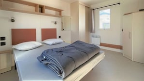 Ein modernes Schlafzimmer mit einem großen Bett, eingebauten Regalen, einem Kleiderschrank und einem Fenster mit Vorhängen.