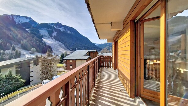 Un balcon offrant une vue sur des montagnes enneigées et une vallée en contrebas.