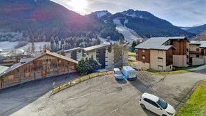 Un paysage montagneux avec des bâtiments, un parking et une piste de ski en arrière-plan.