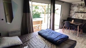 Hotelkamer met een bed, bureau en stoel. Er is een raam met gordijnen, een spiegel en een behang met patroon.