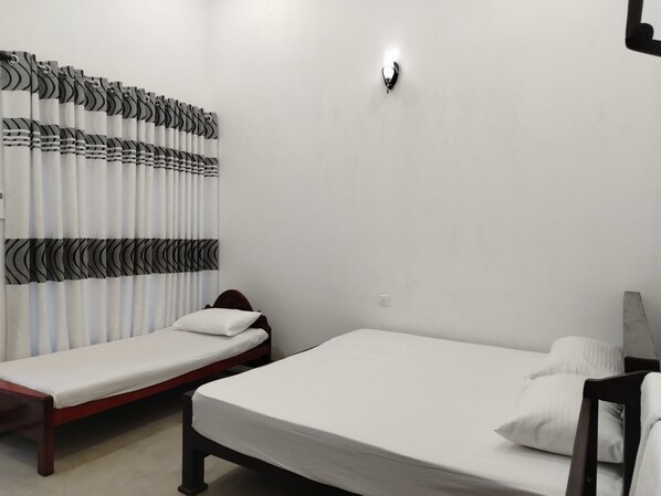 A room with two single beds, a wall-mounted light, and a curtain with a black and white pattern. - Hotel Diamond Palace (Bibile)