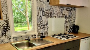 A kitchen with a window, patterned backsplash, and a coffee maker. - Spacious mobile home with terrace in Nibelle (Nibelle)
