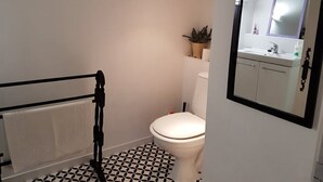 Une salle de bain équipée de toilettes, d’un lavabo, d’un miroir et d’un radiateur.