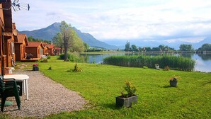 A lakeside property with wooden cabins, a gravel path, and a grassy lawn with potted plants.