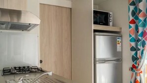 A compact kitchenette with a gas stove, a microwave, and a refrigerator. - Comfortable mobile home in Calvisson for 4 people (Calvisson)