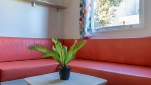 A room with a red sofa, a small table, and a potted plant. - Comfortable mobile home in Calvisson for 4 people (Calvisson)